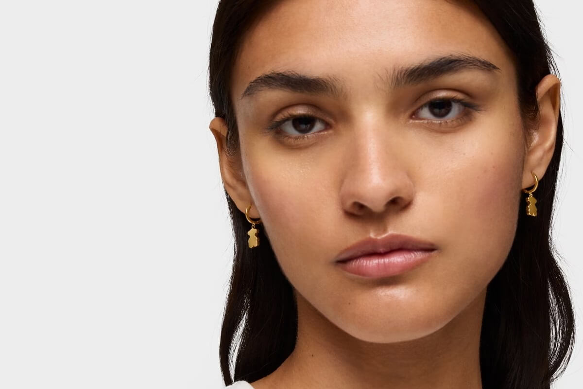 Kobieta w złotych kolczykach TOUS w kształcie misia