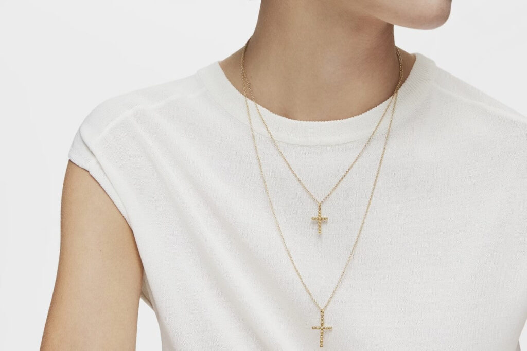 Osoba z zawieszonymi na szyi złotymi krzyżykami idealnymi na komunię Osoba z zawieszonymi na szyi złotymi krzyżykami idealnymi na komunię