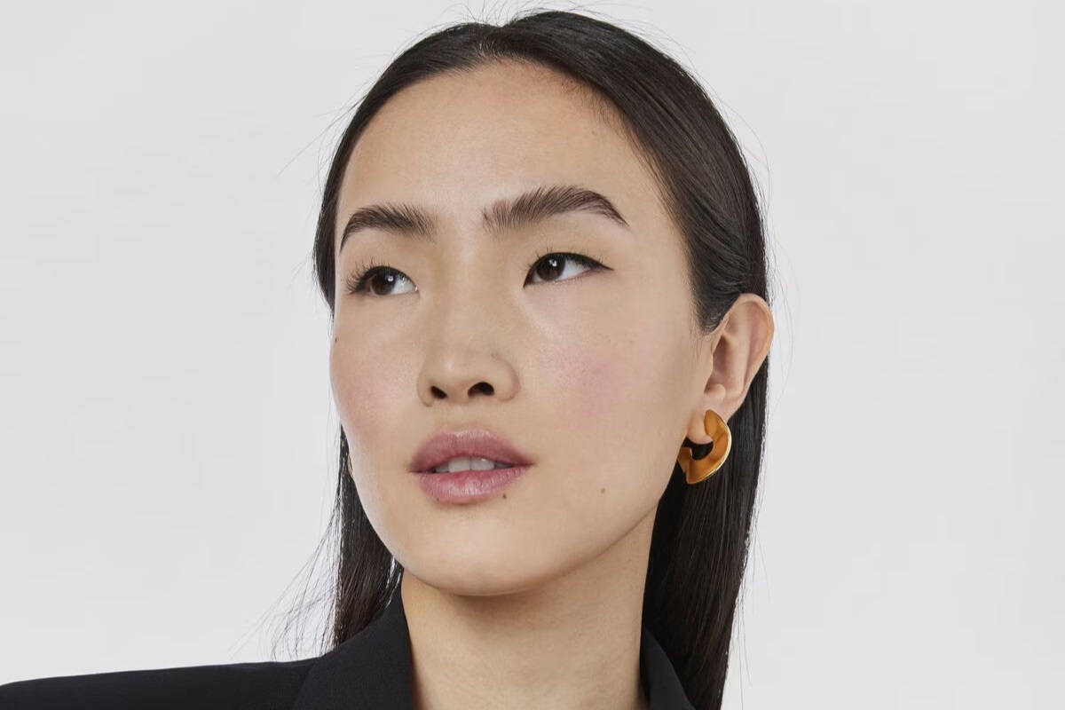 Elegancka kobieta z dużymi, eleganckimi, złotymi kolczykami TOUS na uszach