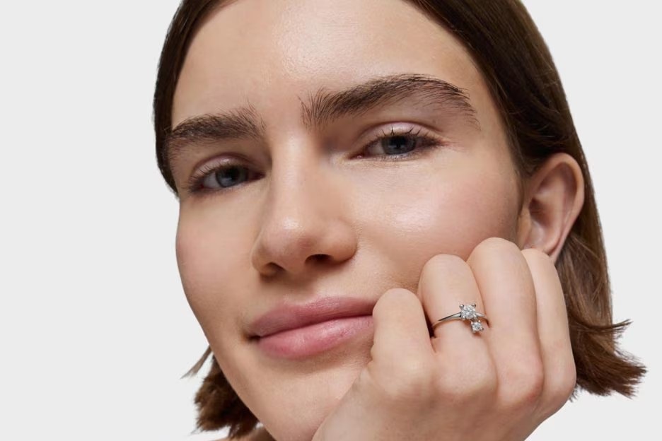 Uśmiechnięta kobieta ze srebrnym pierścionkiem zaręczynowym na ręce