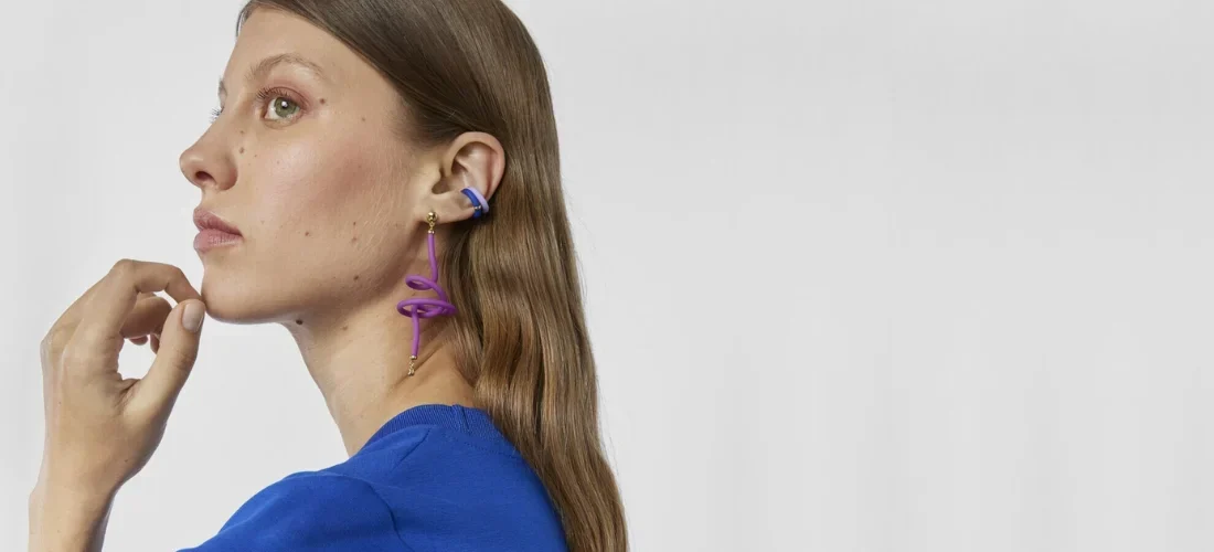 modelo vestida de azul con aretes de colores