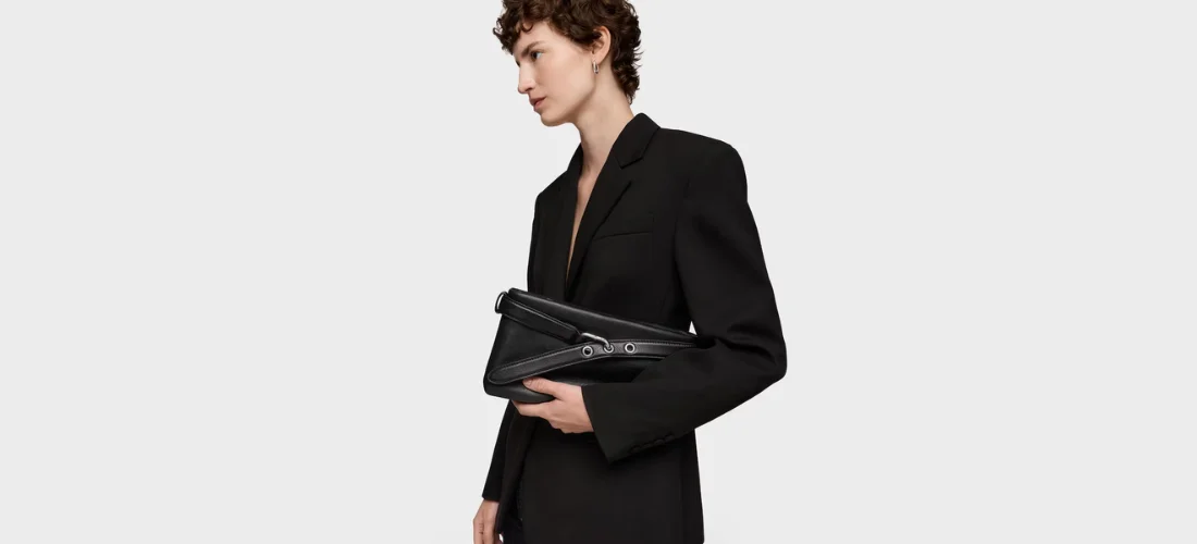 modelo veestida con traje negro y bolso de mano