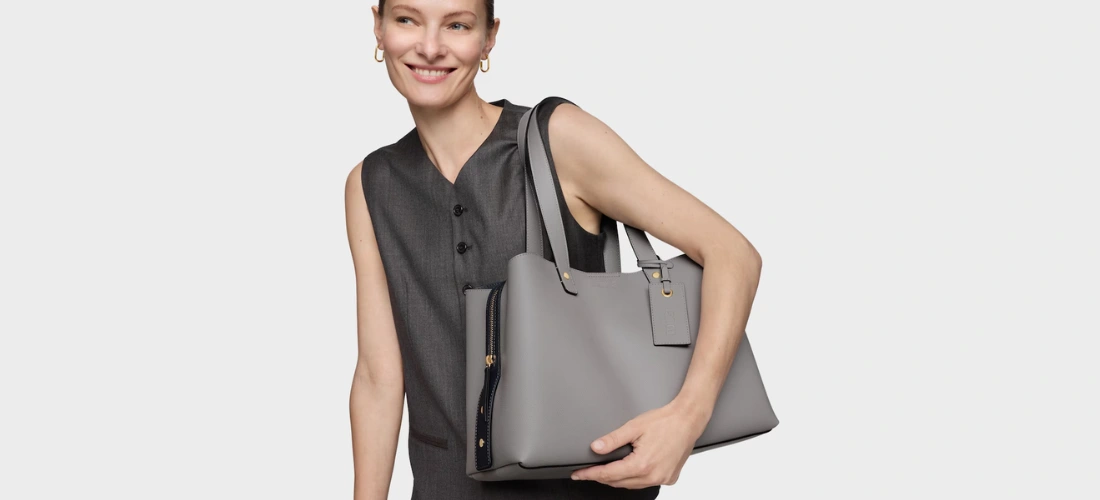 Menina loira sorridente com uma bolsa Tous City cinza médio