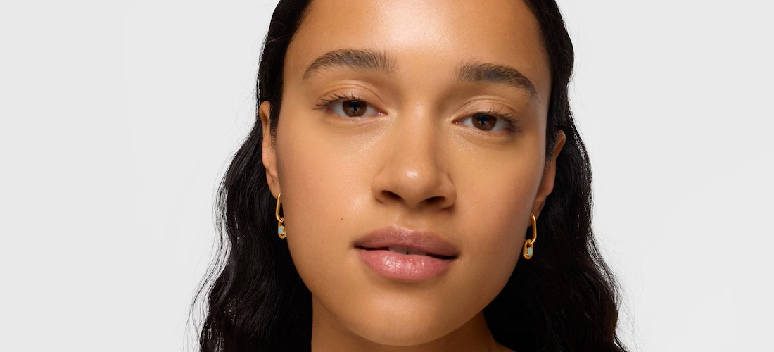 Kobieta ze złotymi kolczykami TOUS z amazonitem na uszach