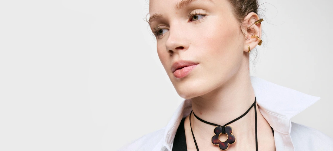 Chica con Collar flor de acero dorado, resina carey y cordón negro 40 mm Galaxy TOUS